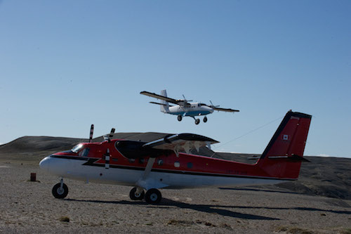 Un Twin Otter bleu qui décolle et un Twin Otter rouge en avant-plan